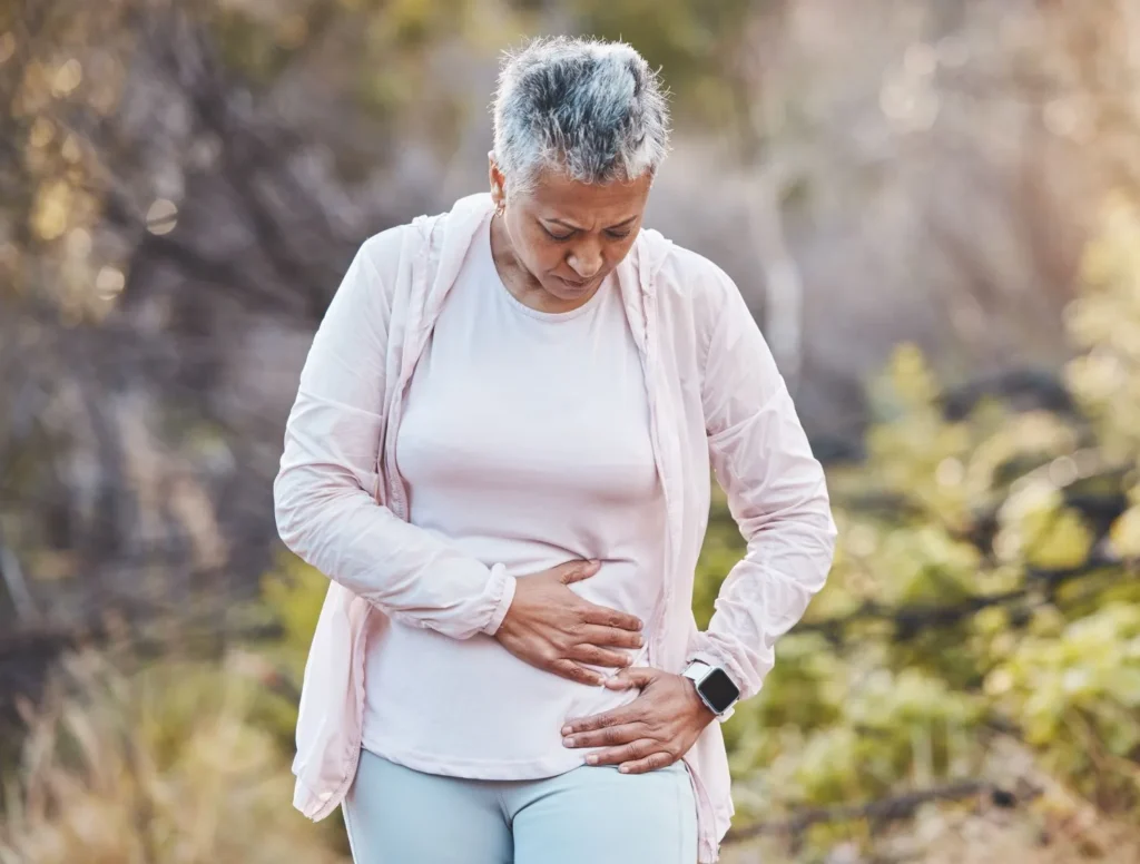 Woman clutching stomach, illustrating weight gain from fatty liver